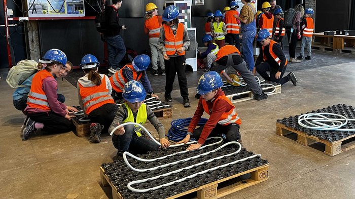 Vivere una giornata in cantiere Bambini con caschi e giubbotti di sicurezza in esercitazione pratica su cantiere