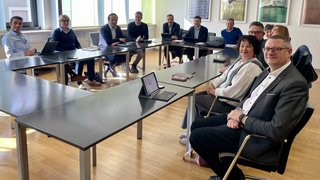 News Personen in einem Besprechungsraum sitzen um Tische und lächeln in die Kamera