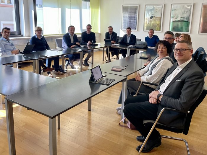 Berufsbildung gemeinsam weiterdenken Personen in einem Besprechungsraum sitzen um Tische und lächeln in die Kamera