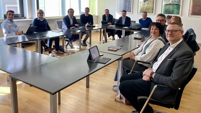 Berufsbildung gemeinsam weiterdenken Personen in einem Besprechungsraum sitzen um Tische und lächeln in die Kamera