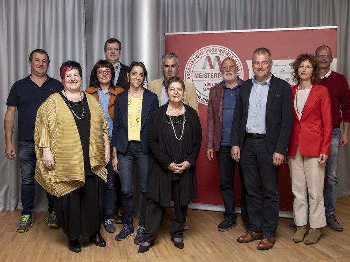 Südtiroler Meisterbund: neuer Rat der Meister gewählt Gruppenfoto von elf Personen vor einer roten Wand mit Meisterbund-Logo