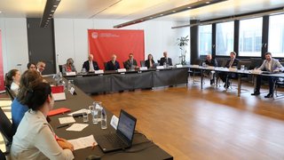 News Menschen sitzen in einem U-förmigen Konferenzraum und nehmen an einer Besprechung teil