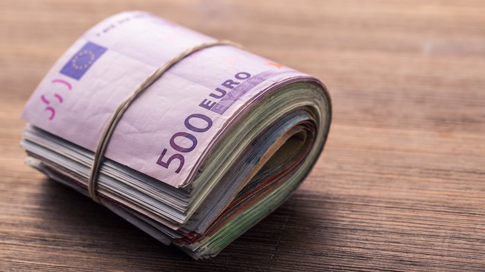 Entlastungspaket für alle Südtirolerinnen und Südtiroler Geldbündel mit 500 Euro Scheinen auf Holztisch