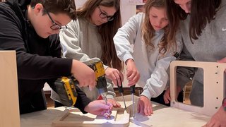 News Jugendliche bauen zusammen mit Werkzeug ein Möbelstück aus Holz zusammen