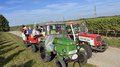 Althandwerker/innen unterwegs: Rundfahrt Weinviertel Traktorfahrt mit zwei Traktoren und Anhänger voller Menschen in einer Weinberglandschaft