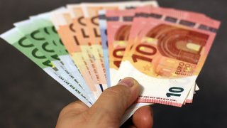 News Hand hält gefächerte Euro-Geldscheine verschiedener Stückelungen