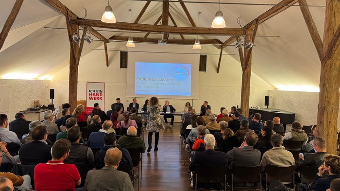 Eppan: Handwerk ist bereit, Verantwortung zu übernehmen Podiumsdiskussion in einem Saal mit Zuschauern und mehreren Teilnehmern am Tisch