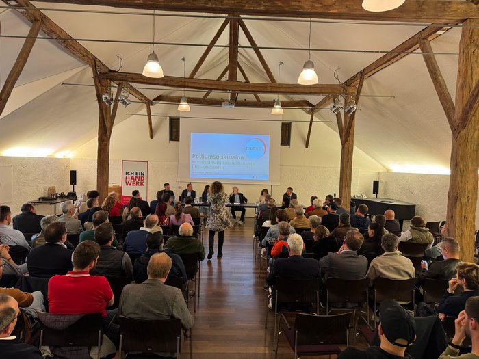 Eppan: Handwerk ist bereit, Verantwortung zu übernehmen Podiumsdiskussion in einem Saal mit Zuschauern und mehreren Teilnehmern am Tisch