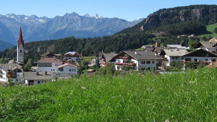 Plattform Land stellt 2026 unter das Jahresthema „Wandel im ländlichen Raum“ Bergdorf mit Kirche und grünen Wiesen vor Alpenkulisse bei klarem Himmel