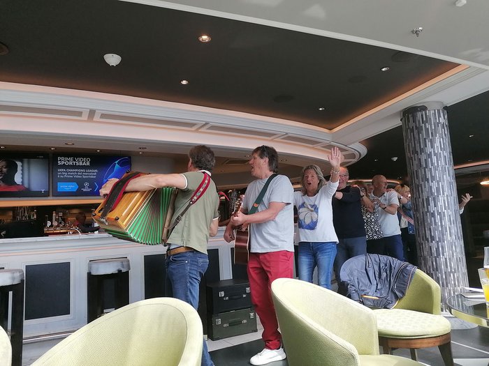 Artigiani anziani in crociera Gruppo di persone che ballano e suonano musica in un bar con fisarmonica e chitarra