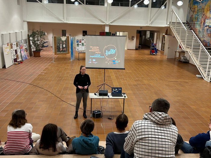 Uno spaccato della vita lavorativa quotidiana Donna presenta davanti a piccolo gruppo in ampia stanza luminosa con gradinate