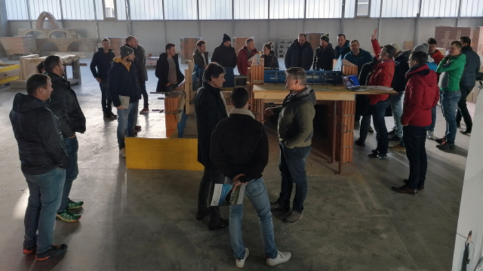 Neue Auflage von „Multitalent Beton“ Gruppe von Menschen in einer Werkhalle bei einer Besprechung