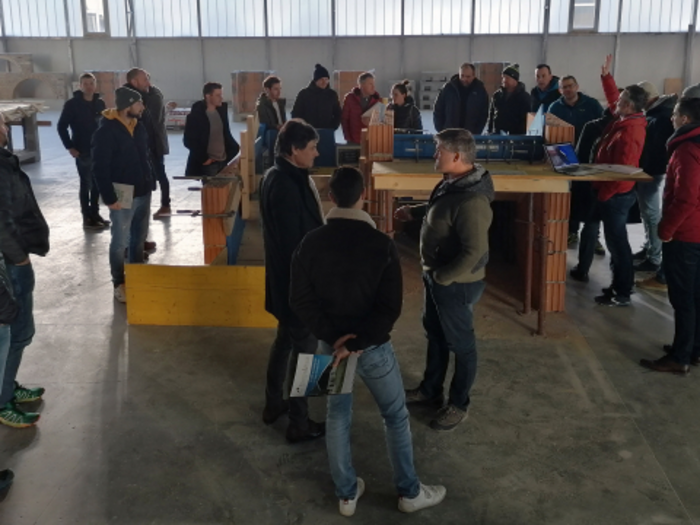 Neue Auflage von „Multitalent Beton“ Gruppe von Menschen in einer Werkhalle bei einer Besprechung