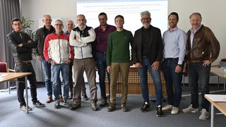 News Gruppe von elf Männern steht in einem Konferenzraum vor einer Präsentation