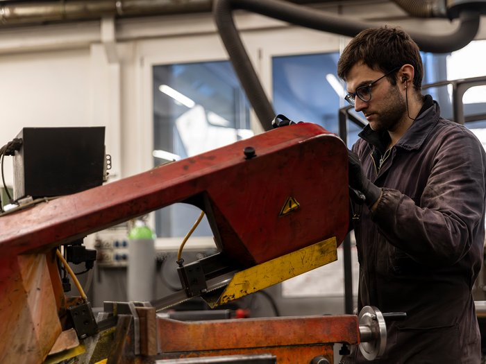 La sicurezza è un lavoro fatto a mano Uomo che utilizza una sega a nastro industriale in un'officina