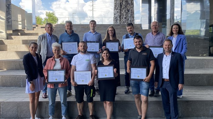 Dieci paladini della sostenibilità nelle imprese artigiane altoatesine Gruppo di persone con certificati su una scalinata durante una cerimonia di premiazione