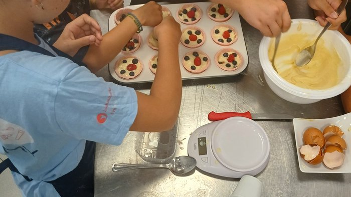 Backspaß und Kreativität – KidsAcademy backt in Kaltern Kinder dekorieren Muffins mit Beeren und Backteig in einer Küche