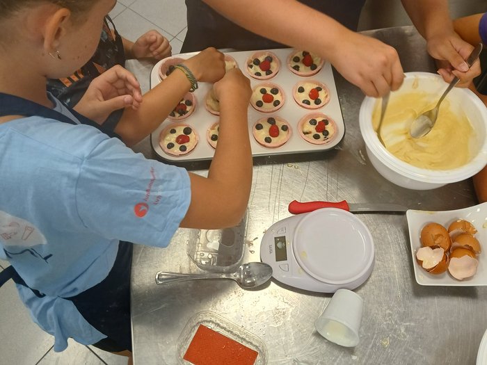 Backspaß und Kreativität – KidsAcademy backt in Kaltern Kinder dekorieren Muffins mit Beeren und Backteig in einer Küche