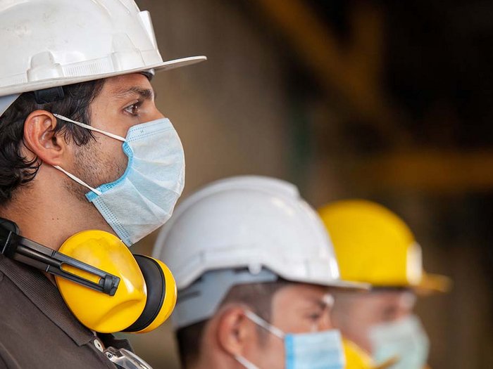 Sicherheit und Hygiene als höchste Priorität Bauarbeiter mit Schutzhelmen und Gesichtsmasken stehen nebeneinander