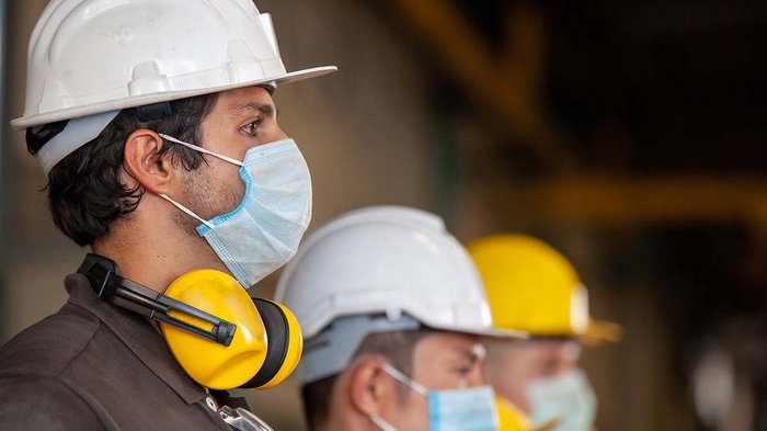 Sicherheit und Hygiene als höchste Priorität Bauarbeiter mit Schutzhelmen und Gesichtsmasken stehen nebeneinander