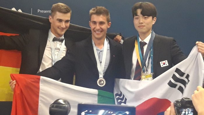 WorldSkills 2022 Special Edition: Zimmerer Marcel Bolego holt Silbermedaille Drei Medaillengewinner mit den Flaggen von Deutschland, Italien und Südkorea