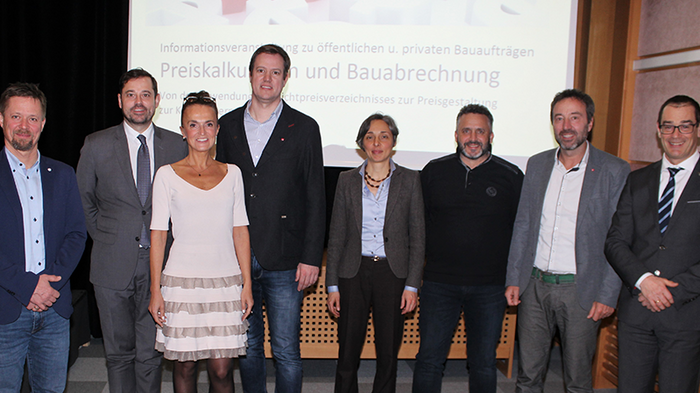 Auf dem richtigen Weg zu den öffentlichen Aufträgen Gruppenfoto von acht Personen vor Präsentationsbildschirm bei einem Bau-Event