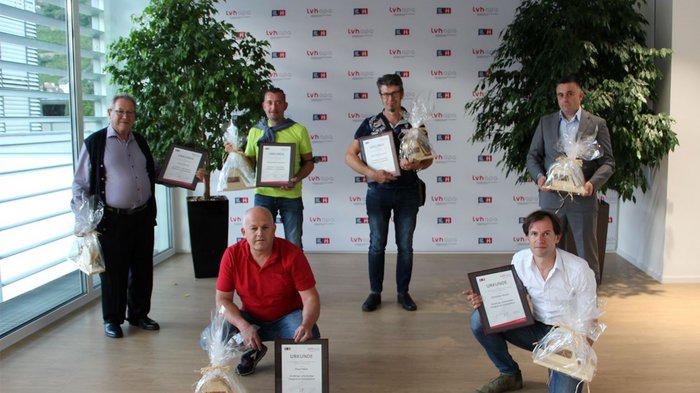 lvh-Kaminkehrer lassen das Jahr Revue passieren Sei uomini con certificati e regali in una stanza moderna