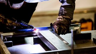 News Person arbeitet mit Schutzkleidung und Schweißgerät an Metallrahmen