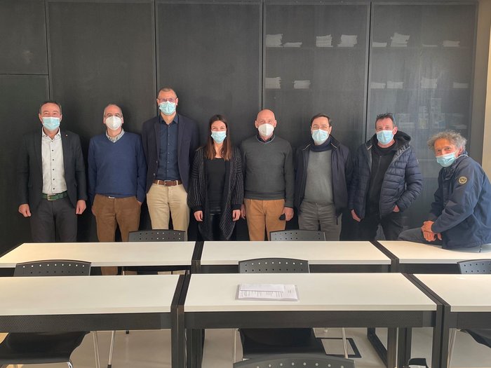 Bauarbeiterkasse: neue Vereinbarung für die Arbeitskleidung Gruppe von zehn Personen mit Masken in einem Besprechungsraum hinter Tischen