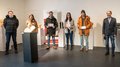 „Kunst ist schön“ Gruppe von sechs Personen in einer Galerie mit Skulpturen, drei halten Zertifikate