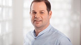 News Porträt eines Mannes mit blauem Hemd vor hellem unscharfem Hintergrund