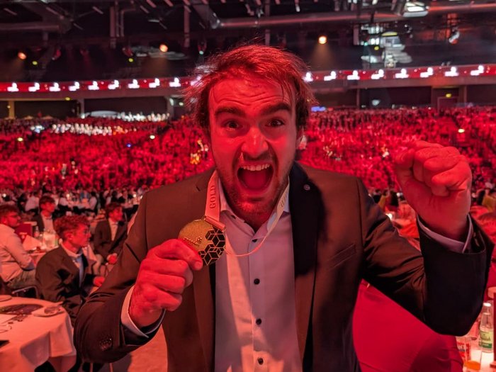 Titolo europeo per i giovani artigiani altoatesini: lvh si congratula per i successi straordinari agli EuroSkills 2025 Uomo festeggia con medaglia d'oro in una grande cerimonia davanti a un pubblico rosso