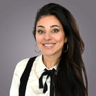 Rossella Bova Donna sorridente con capelli neri lunghi e orecchini d'oro su sfondo grigio