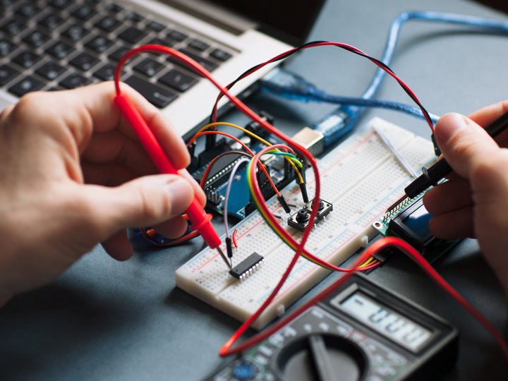 Ausbildung Person misst mit Multimeter auf einem Steckbrett mit elektronischen Bauteilen