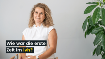 Jobs Frau in weißem Oberteil sitzend neben einer Pflanze vor weißer Wand