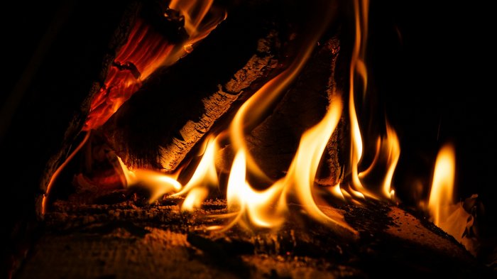 Vorsicht beim Verheizen von Christbäumen Brennendes Holzfeuer in dunkler Umgebung