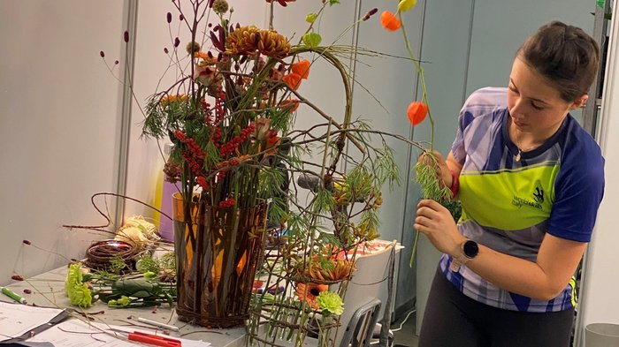 WorldSkills 2022: “Entrambe hanno dato tutto!“ Donna sistema fiori colorati in un vaso su un tavolo in una stanza