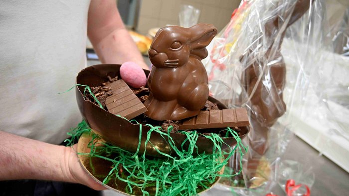 Oster-Spezialitäten mit Herz und Tradition Person hält eine Schale mit Schokoladenhase und Schokoladentafel