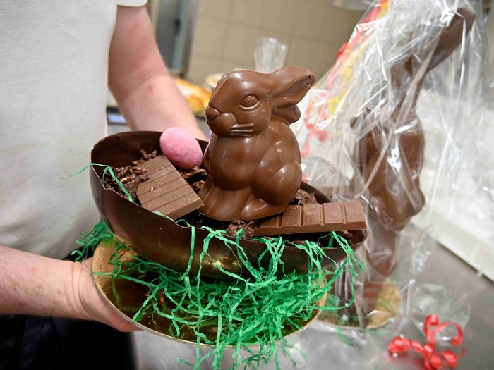 Oster-Spezialitäten mit Herz und Tradition Person hält eine Schale mit Schokoladenhase und Schokoladentafel