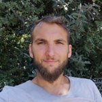 Klausen Porträt eines Mannes mit Bart vor grünem Laub