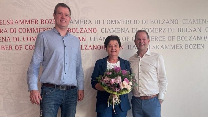 Drei Frauen aus dem Handwerk erobern die Führungsebene Drei Personen stehen vor der Kammer der Wirtschaft von Bozen, Frau hält Blumenstrauß