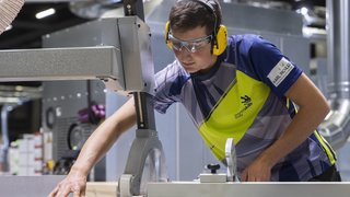 News Facharbeiter mit Schutzausrüstung an einer Holzbearbeitungsmaschine