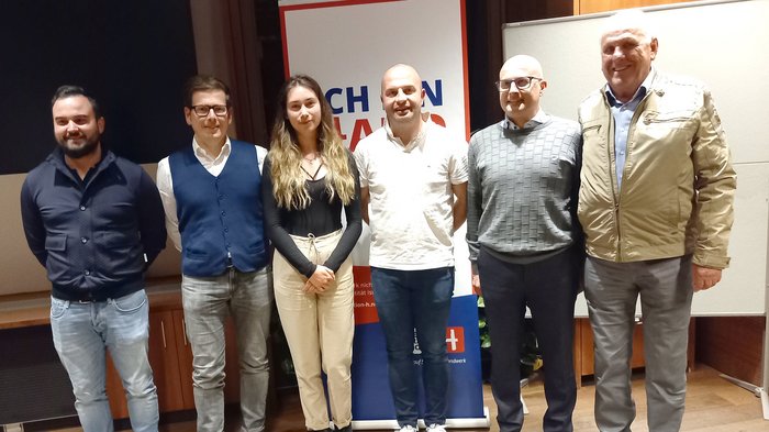 Handwerk: Innovativ. Leistungsstark. Nachhaltig Sechs Personen stehen vor einer Werbetafel in einem Raum