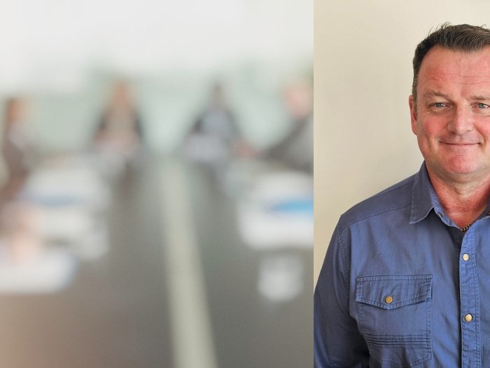 L'artigianato locale genera valore aggiunto Ritratto di un uomo sorridente con camicia blu davanti a riunione sfocata