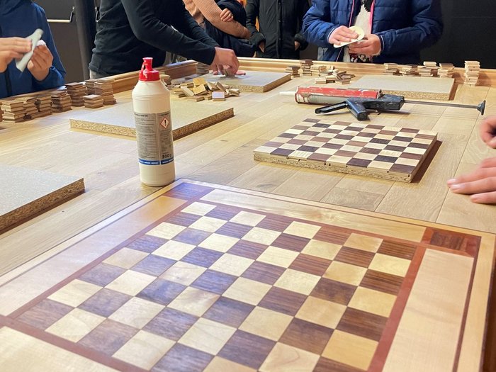 A San Genesio un’intera giornata dedicata all’artigianato Ragazzi lavorano su scacchiere di legno in una stanza con spettatori