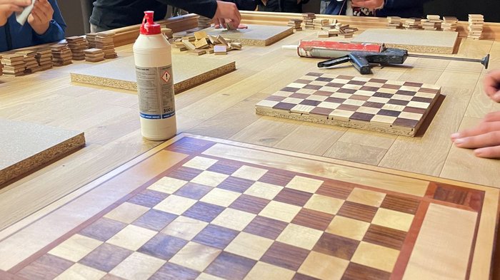 Tag des Handwerks in Jenesien Jugendliche arbeiten an Holzschachbrettern in einem Raum mit Zuschauern