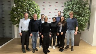 Formazione professionale Foto di gruppo di otto persone davanti a una parete con logo LVH-APA e piante verdi