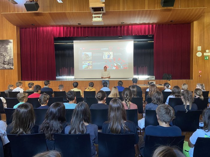 Riprende la campagna d’informazione promossa da lvh.apa nelle scuole Studentessa presenta davanti a un gruppo di studenti in un auditorium
