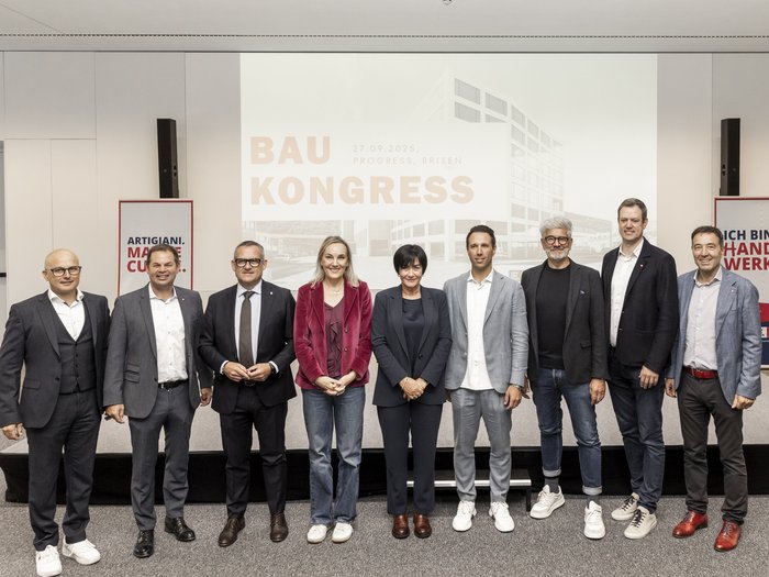 Baukongress 2025: Zukunft bauen durch Kooperation Gruppenfoto von zehn Personen vor einer Leinwand mit Schrift Baukongress