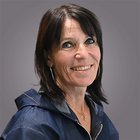 Marlene Puner Ritratto di una donna sorridente con capelli scuri su sfondo grigio